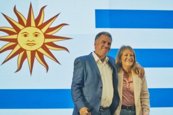 Orsi y Cosse se abrazan con la bandera uruguaya de fondo